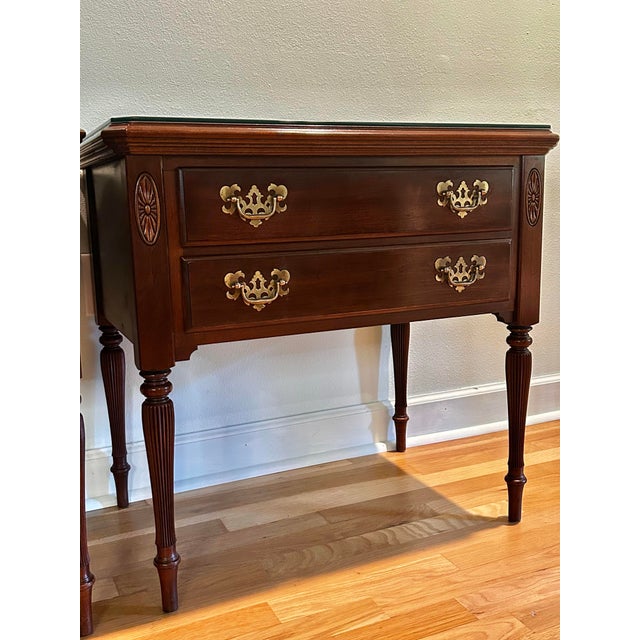 A handsome pair of vintage Ethan Allen Georgian Court nightstands crafted in rich mahogany with elegant Federal and...
