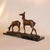 A patinated bronze group of a pair of grazing deer set over a naturalist base on a marble plinth. Signed to bronze....