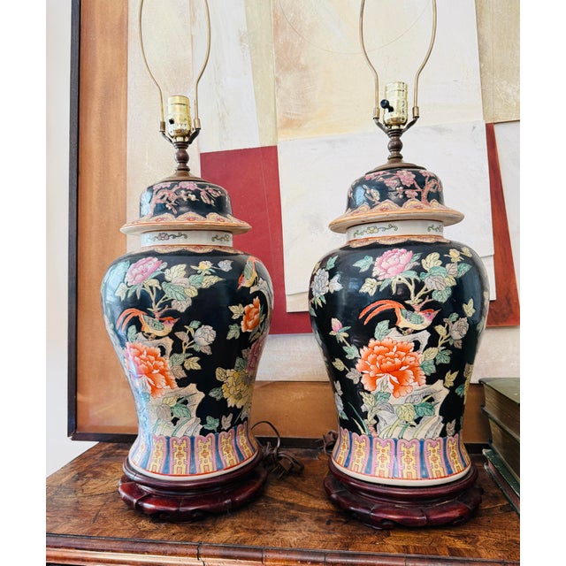 Striking pair of vintage Chinese Famille Noire-style porcelain table lamps featuring a rich black ground decorated with...