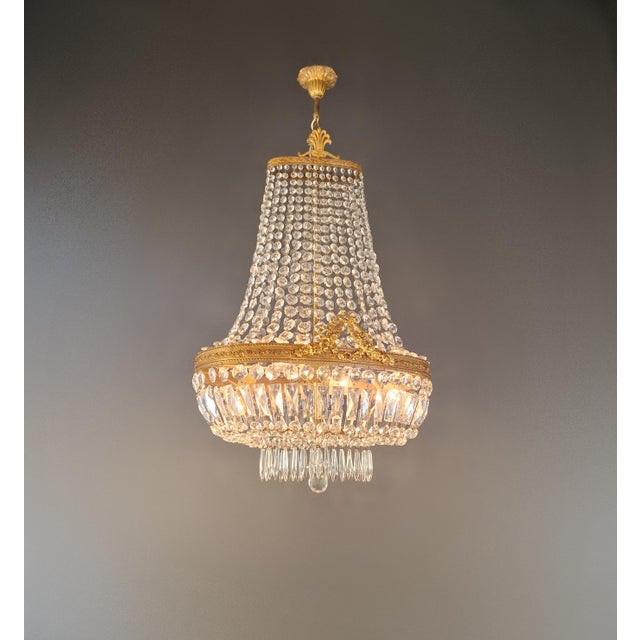 This Empire Revival-style oval crystal chandelier combines an ornate brass frame with a dense arrangement of faceted...