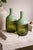A beautifully crafted pair of handmade art glass bottles featuring a sophisticated two-tone green palette. Each piece...