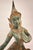 A large bronze sculpture of a seated figure rendered in a classic Thai or Southeast Asian style, with a tall, pointed...