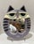 Whimsical sculptural cat-form wall mirror dated 1981, with lavender-gray body, black striped detailing, cream face, pale...