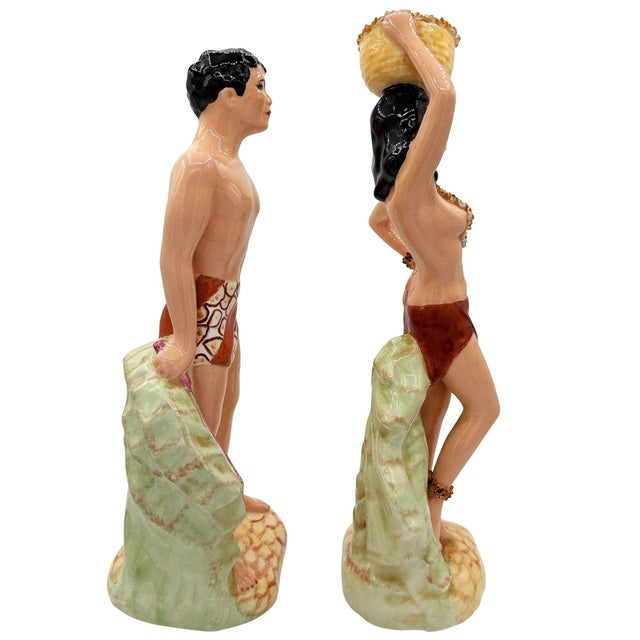 This pair of vintage mid-century ceramic figurines depicts a stylized Polynesian man and woman. Hand-painted with a glossy...