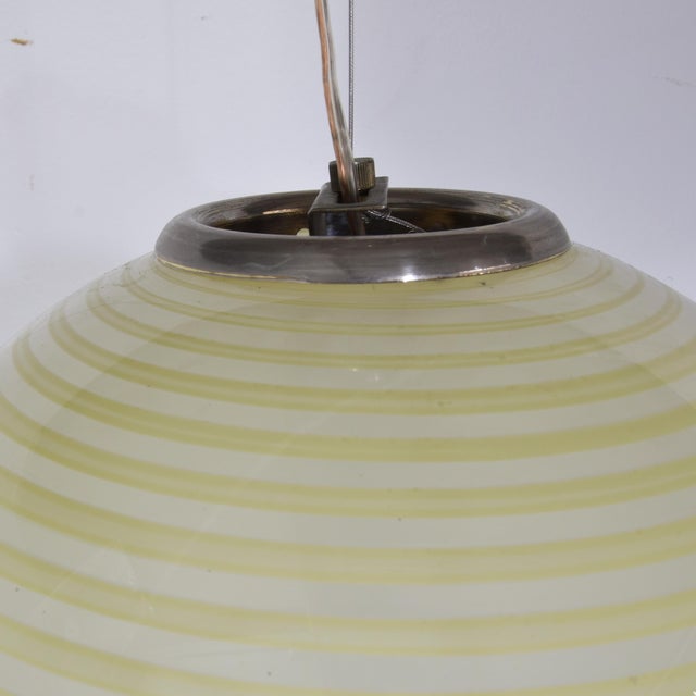 This pendant lamp attributed to Venini stands out for its elegant spherical shape and refined craftsmanship in Murano...