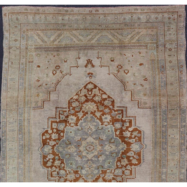 Measures: 6'10 x 10'5 This softly colored Oushak carpet rests beautifully upon a field of elegant light taupe. A large...