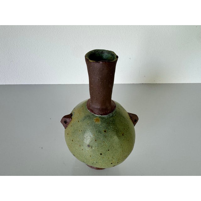This charming vintage pottery vase is a testament to artisan craftsmanship. Its unique spherical body features a soft...