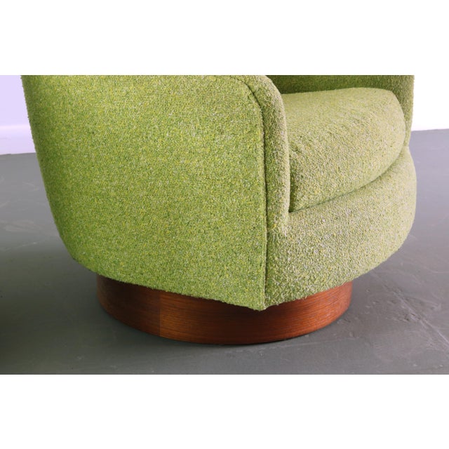 Handsome pair of swivel chairs attributed to Milo Baughman. In stunning original upholstery and resting on a medium walnut...
