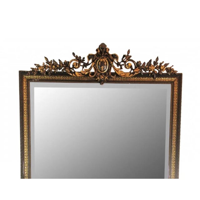 Antique empire beveled mirror in a gorgeous hand carved black wood frame that is gilded in a dore wood floral design. The...