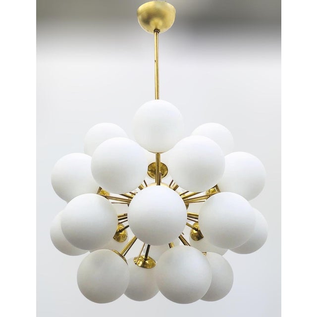 Italian sputnik chandelier with 24 matte white Murano glass globes mounted on brass frame in unlacquered natural brass...