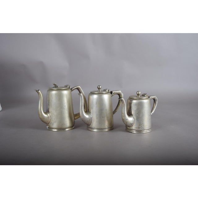 Set of three graduated English silver-plated coffee pots from the 1930s. Each has a hinged lid, curved spout and shaped...