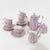 A stunning vintage porcelain tea set featuring a delicate pink floral design, vertical stripe patterns, and gold trim....