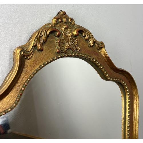 This decorative Vintage French wall mirror features an ornate shaped wooden frame with a warm gilt finish and classic...