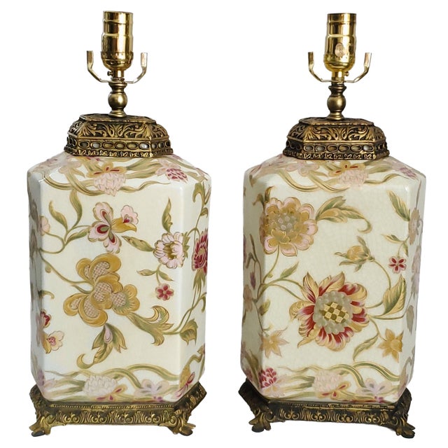 Offering a pair of vintage Chinese porcelain table lamps with flowers and leaves with gold detailing, circa Late 20th...