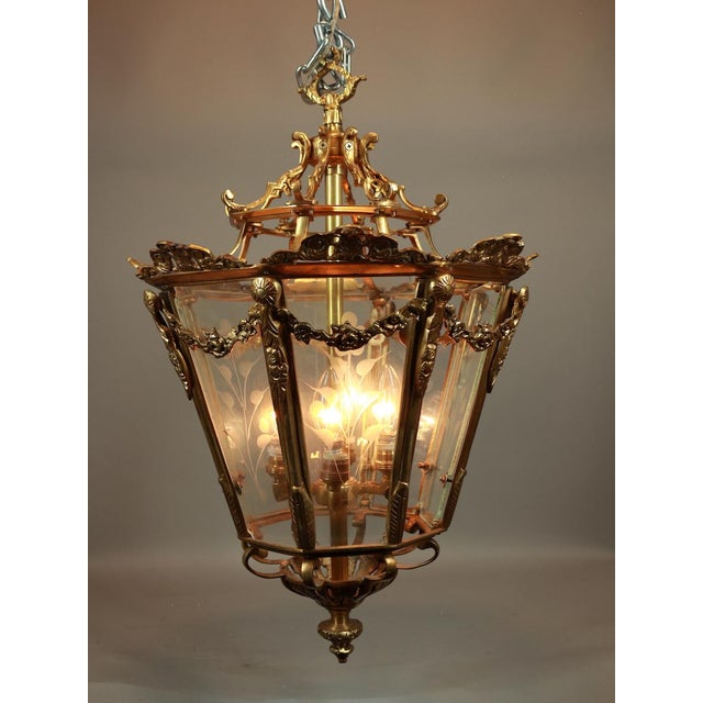 A refined circa 1970 French Louis XVI–style lantern chandelier, crafted from bronze with a warm gold patina and clear...
