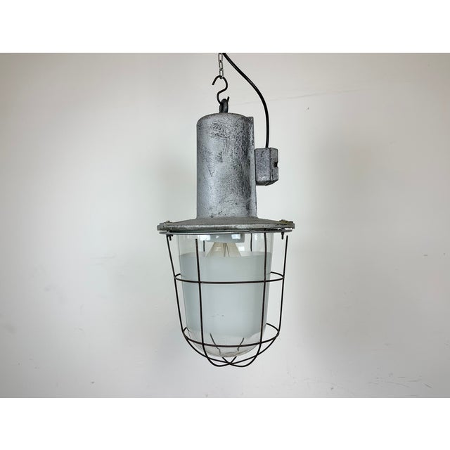 Large industrial factory hanging lamp made in former Czechoslovakia during the 1960s. It features a cast aluminium body, a...