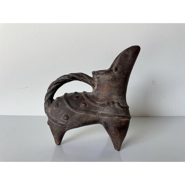 This sculptural pottery tripod ewer, or gui, is designed in the style of vessels from the Chinese Neolithic period....