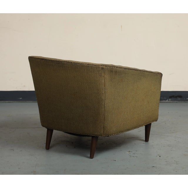 A classic vintage midcentury style Italian lounge chair. The chair is upholstered in a textured fabric with a subtle...