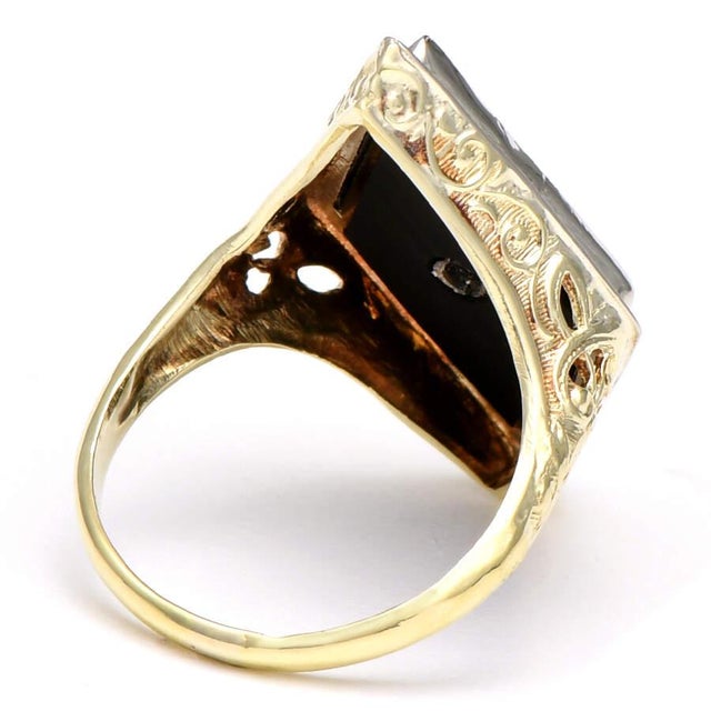 Featuring ornate onyx, this pristine piece sparkles with a dazzling diamond at the center. A dynamic gold setting...
