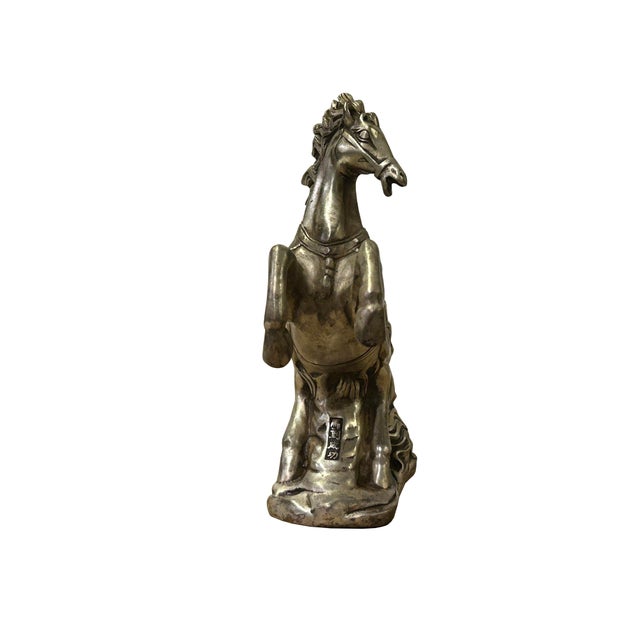This striking statuette captures the dynamic energy of a horse in mid-rear, a powerful symbol of victory and success....