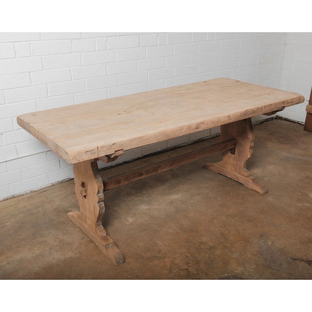 This rustic trestle dining table features a solid plank top with smoothed edges and a generously thick profile. The carved...