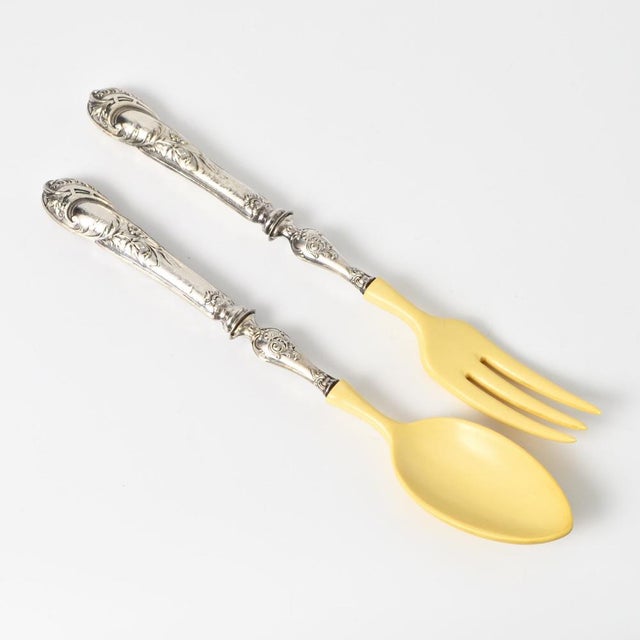 Set of two salad servers in original box. Servers are made of faux ivory and 800 fineness silver handles. Box size: 32 cm...