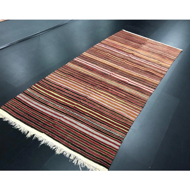 This is a vintage kilim rug. The piece was handmade in the 1960s.