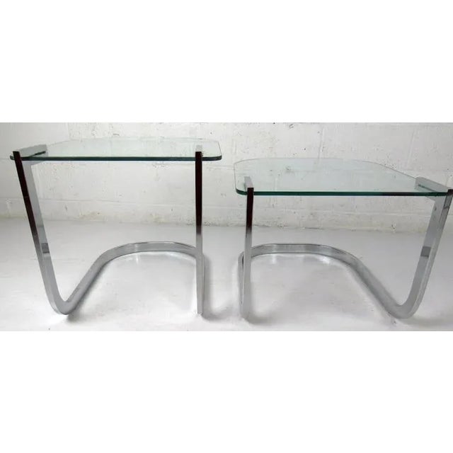 Stylish pair of stacking vintage-modern nesting tables by Design Institute Of American, features bent chrome base and...