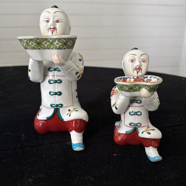 A graduating set of two vintage hand-painted porcelain figurines by the Hungarian manufacturer Herend. Formed as kneeling...