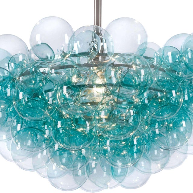 Light and airy, the Bubbles chandelier radiates light through a cluster of hand blown glass globes. The tiered metal frame...