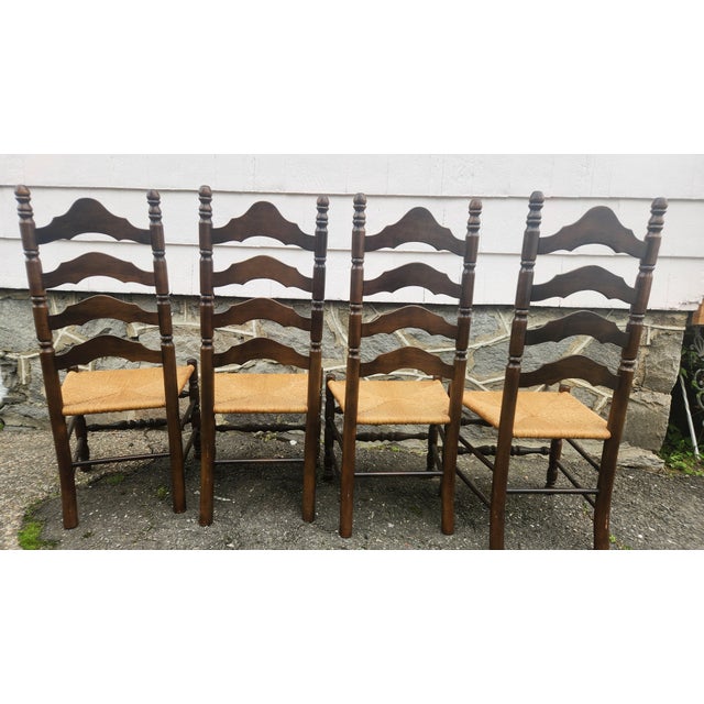 Charming set of 6 vintage ladder-back dining chairs featuring dark stained wood frames, rush woven seats, turned posts,...