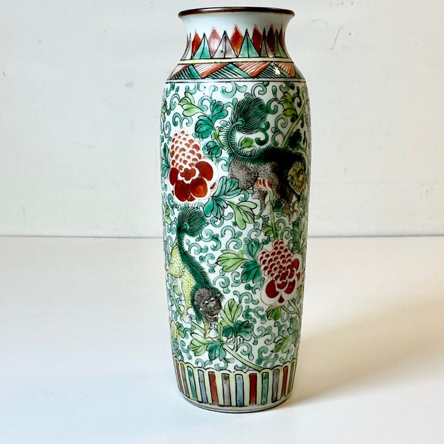 A lovely hand painted Chinoiserie Ceramic Vase. It features four Foo Dogs among persimmon Lotus blooms and green vines and...