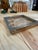 A decorative square tray featuring an organic cork composition beneath a clear glass surface, framed by a broad, silver-...