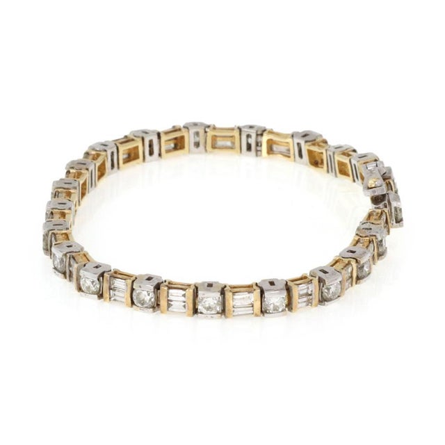 This is an elegant diamond bracelet, it is crafted from 14k yellow and white gold featuring alternating round and baguette...
