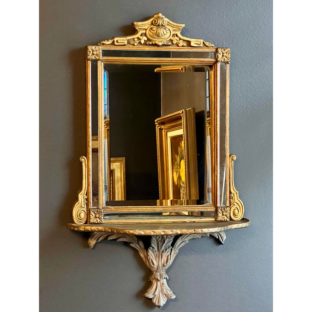 A lovely 19th century Adam style French giltwood mirror with an integrated shelf. This striking, petite mirror will...
