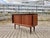 Elegant Mid-Century teak sideboard featuring sliding doors and beautiful detailing on both the legs and door handles. The...