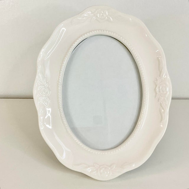 This is a pretty Oval Ceramic Picture Frame with back easel for table top display. It features a rose design in the white...