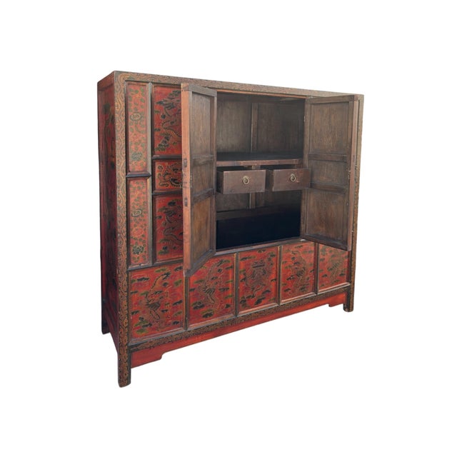A late 19th Century Tibetan cabinet made with hand hewn carved wood. Hand painted throughout, with auspicious serpentine...