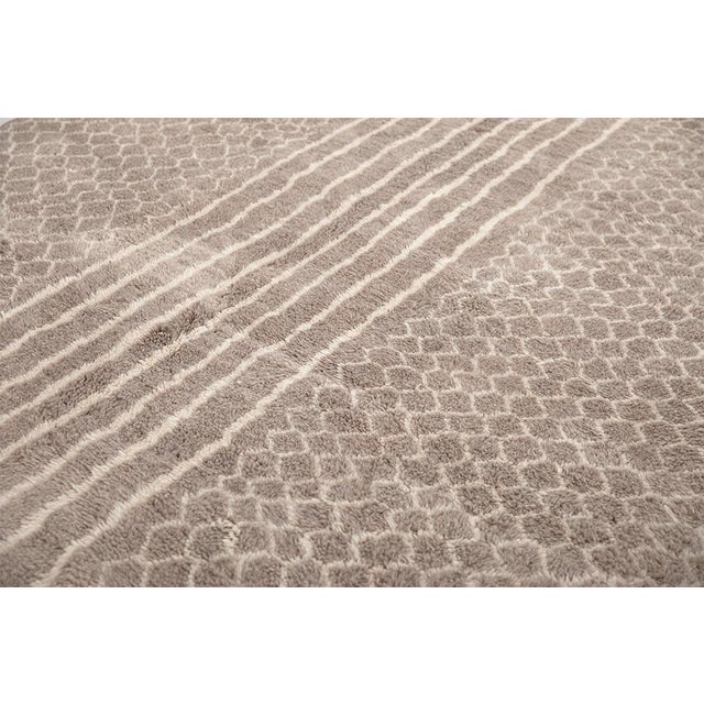 Timeless hand-knotted wool rug featuring intricate honeycomb patterns along the sides and vertical striped detailing in...