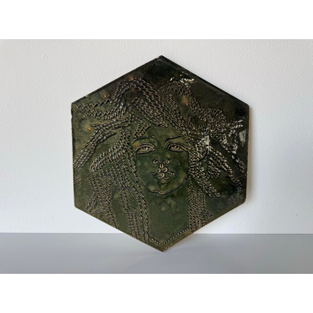 This striking vintage ceramic wall plaque by Susan Steven features a deeply textured figural portrait rendered in rich,...