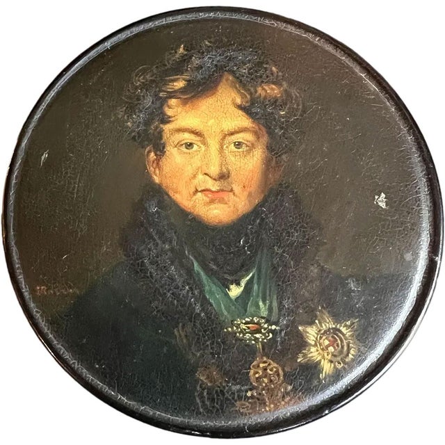 DETAILS An antique English black lacquer, papier-mâché table-top snuff box of round form with fitted lid. After an...