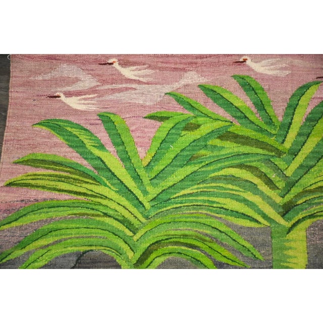 A vintage rug with a scene of egrets in a tropical setting. Unsigned. 38” wide. 43” deep.