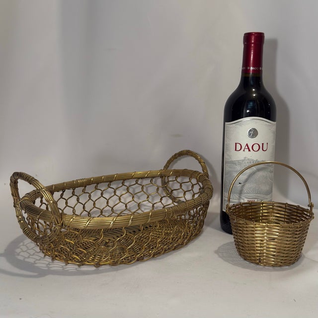 An authentic mid-century set of two hand-woven brass wire tabletop baskets by Castilian Imports, featuring an exceptional...
