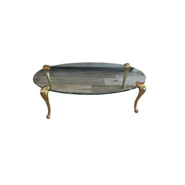 A striking Hollywood Regency coffee table attributed to P.E. Guerin, featuring an elegant oval glass top supported by four...