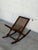 A distinctive Danish rocking magazine rack featuring a dark wood frame, turned supports, curved rockers, and woven cane...