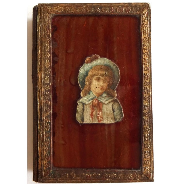 An antique French faux book box with a decoupage of a young girl on the front cover. Wood base, leatherette paper,...