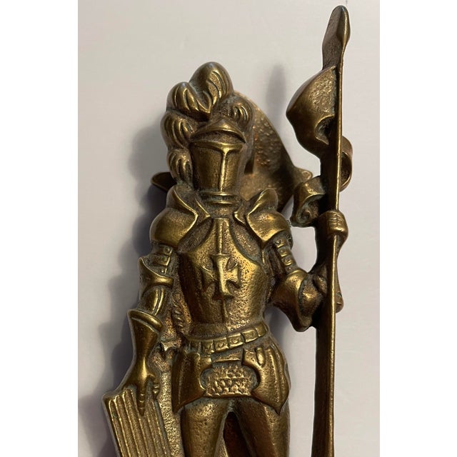 Vintage brass door knocker in the form of a knight with a shield, lance, sword and outfitted in armor. Marked on the back...