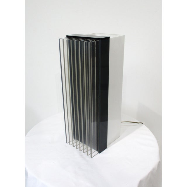 A unique table lamp with clear Lucite finned front, black matching band and white opaque matching body. An inline dimmer...