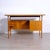 This vintage wooden desk in mid-century Italian style from the 1950s features three side drawers and a glass top. The...