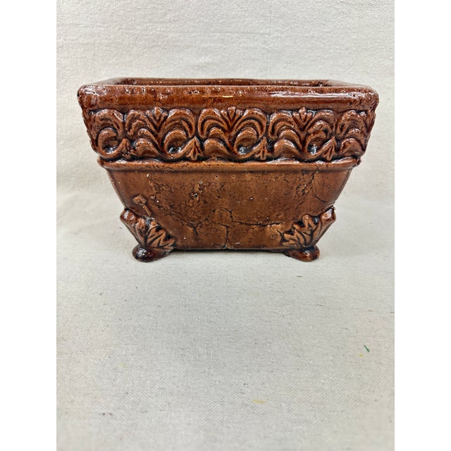 Brown ceramic footed planter/cachepot with embossed floral design and lion feet distributed by Hosley Company. This is a...